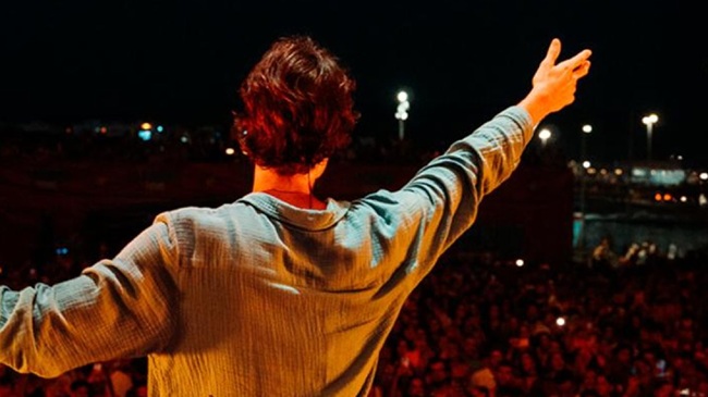 Cantante Hey Kid (Santi Vancells) de espaldas con el brazo levantado frente a una multitud entregada en su concierto de Salamanca