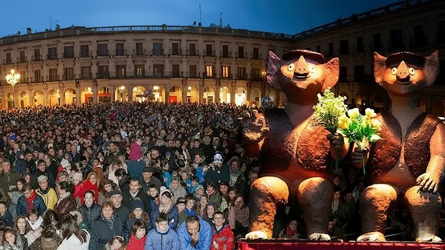 Multitud de personas celebrando la Rifa de San Antón en la Plaza de España de Vitoria-Gasteiz con figuras tradicionales de cerdos de chocolate.