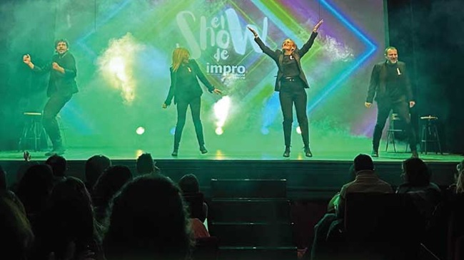 Cuatro actores de ImproValladolid en el escenario del Teatro Zorrilla durante una función de El Show de Impro con luces verdes y humo.