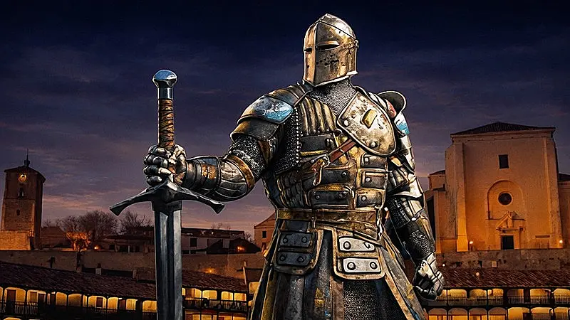 Guerrero medieval con armadura completa y espada en primer plano ante la Plaza Mayor de Chinchón al atardecer.